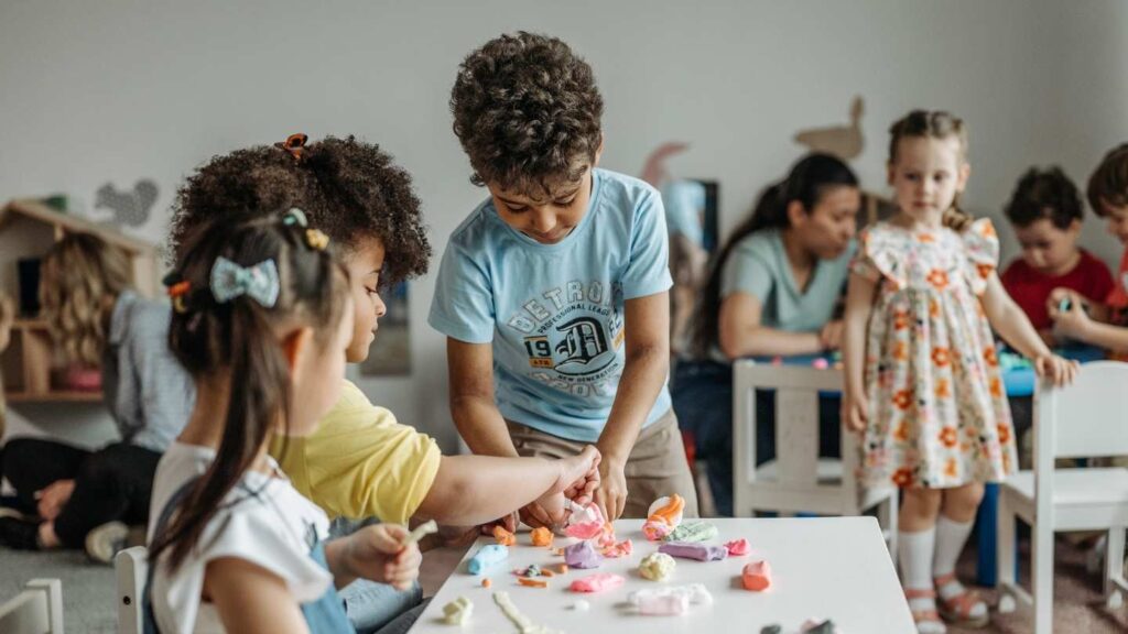 Preschool children playing with colorful modeling clay during a hands-on sensory learning activity.